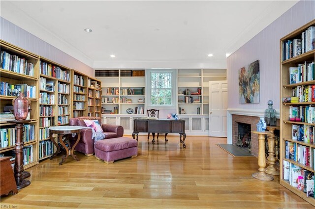 sitting room with a fireplace, ornamental molding, and light hardwood / wood-style flooring