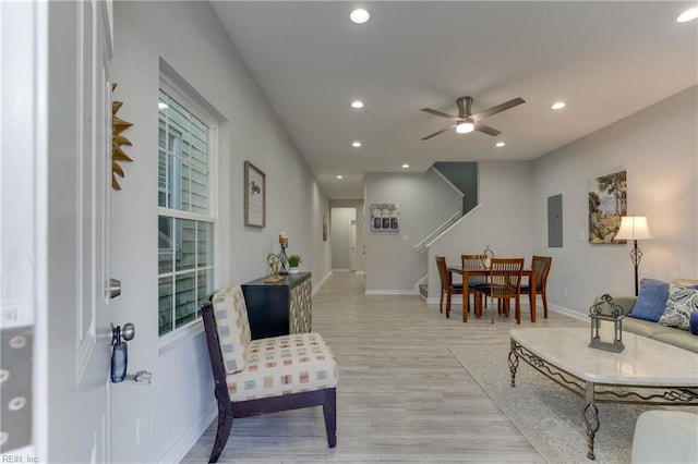 living room with electric panel, ceiling fan, and light hardwood / wood-style floors