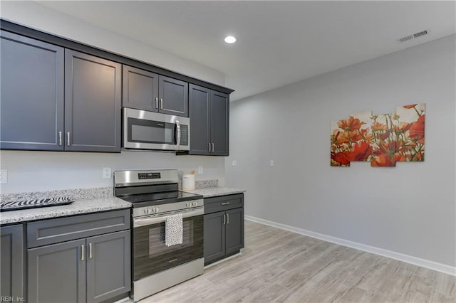 kitchen with light stone countertops, light hardwood / wood-style flooring, and stainless steel appliances