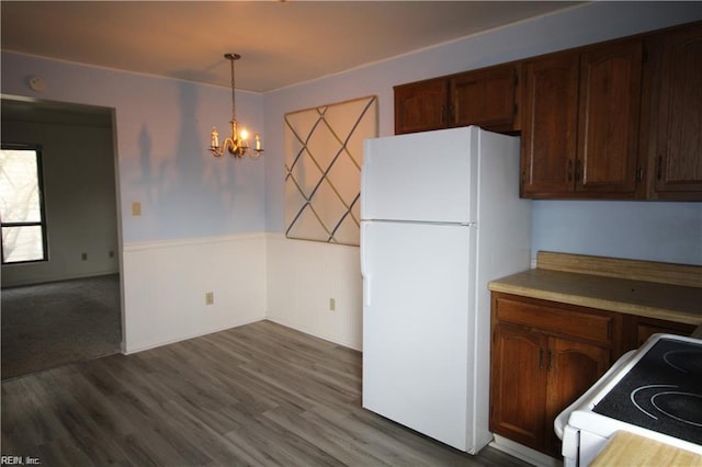 kitchen featuring pendant lighting, an inviting chandelier, white refrigerator, hardwood / wood-style flooring, and range