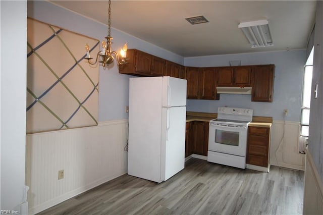 kitchen with pendant lighting, light wood-type flooring, white appliances, and a chandelier