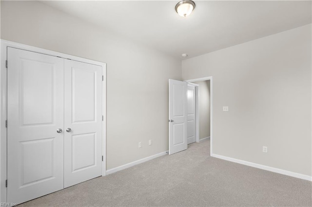 unfurnished bedroom featuring light carpet and a closet