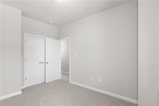 unfurnished bedroom with light colored carpet and a closet