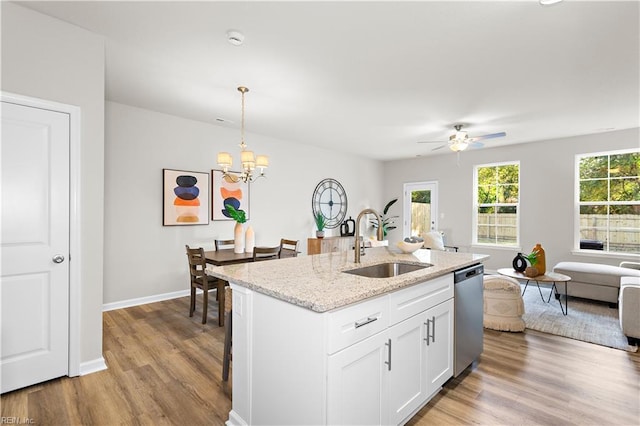 kitchen featuring dishwasher, sink, decorative light fixtures, white cabinets, and light wood-type flooring