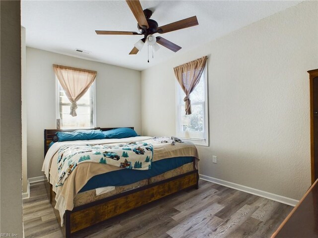 bedroom with ceiling fan, dark hardwood / wood-style flooring, and multiple windows