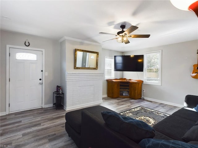 living room featuring hardwood / wood-style flooring, ceiling fan, and crown molding