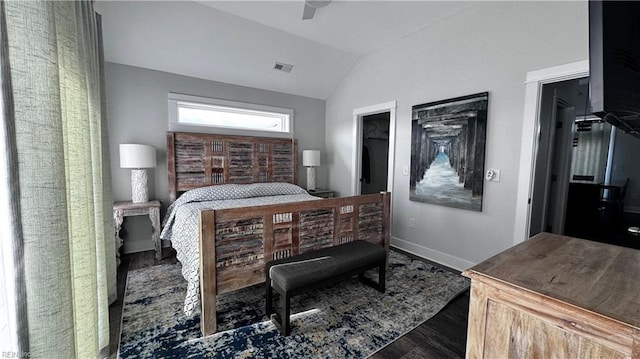 bedroom featuring ceiling fan, dark hardwood / wood-style floors, lofted ceiling, a walk in closet, and a closet