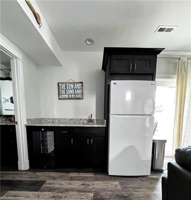 kitchen featuring a textured ceiling, light stone counters, white fridge, and dark hardwood / wood-style floors