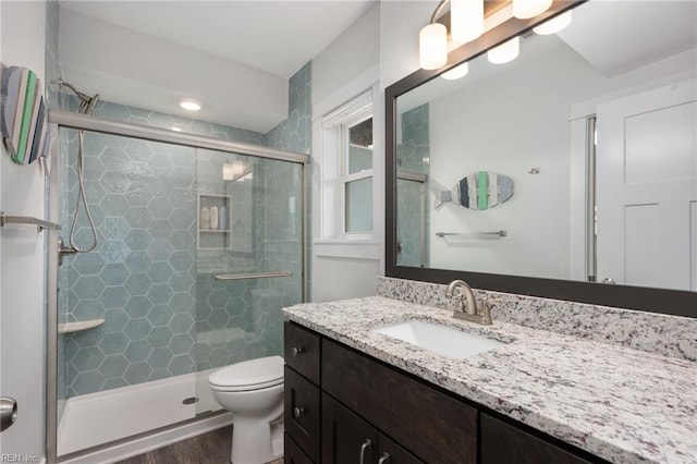 bathroom featuring hardwood / wood-style flooring, vanity, toilet, and a shower with shower door