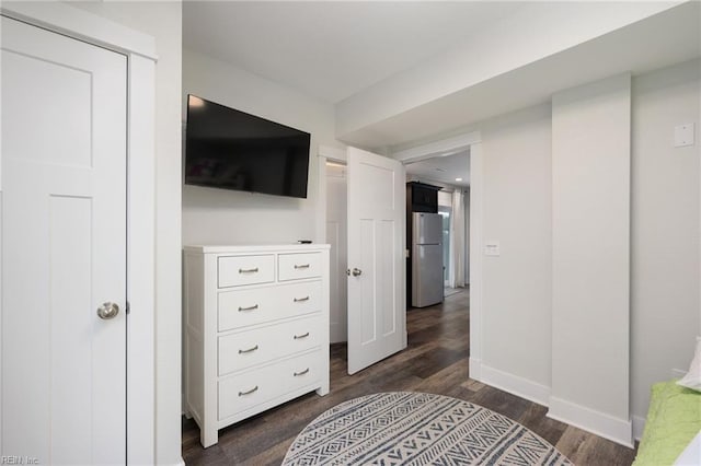 bedroom featuring stainless steel refrigerator, a closet, and dark wood-type flooring