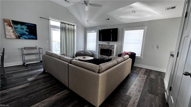 living room with dark hardwood / wood-style floors, vaulted ceiling, ceiling fan, and a stone fireplace