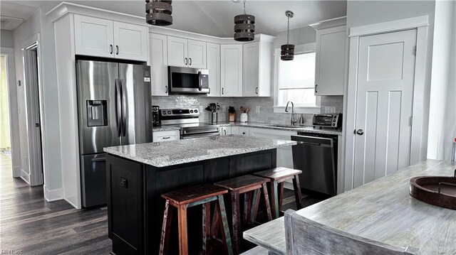 kitchen with pendant lighting, sink, a kitchen island, white cabinetry, and stainless steel appliances