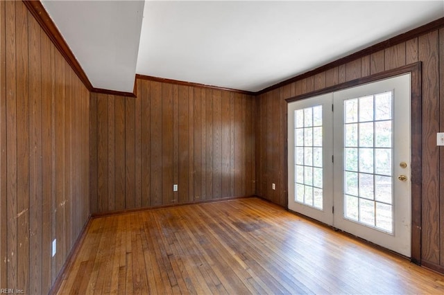 unfurnished room with wooden walls, ornamental molding, and hardwood / wood-style flooring