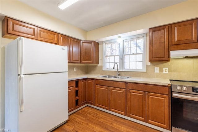 kitchen featuring backsplash, sink, light hardwood / wood-style flooring, stainless steel range oven, and white fridge