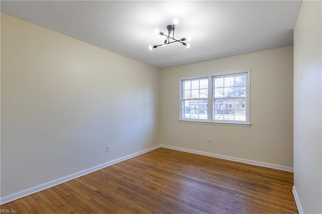 empty room with dark hardwood / wood-style flooring and an inviting chandelier