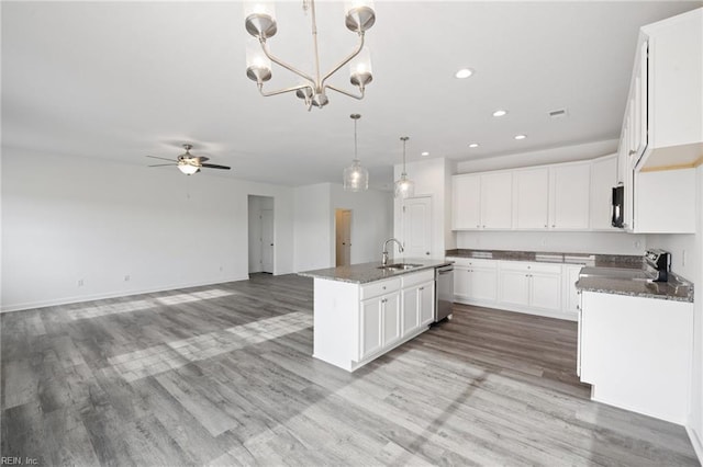 kitchen featuring ceiling fan with notable chandelier, sink, white cabinetry, hanging light fixtures, and an island with sink