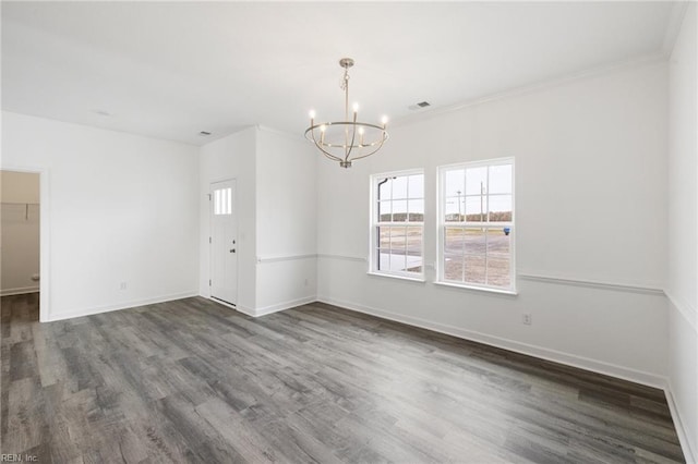 empty room featuring a chandelier, dark hardwood / wood-style flooring, and crown molding