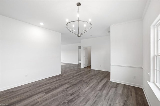 spare room featuring dark hardwood / wood-style flooring, ornamental molding, and a notable chandelier