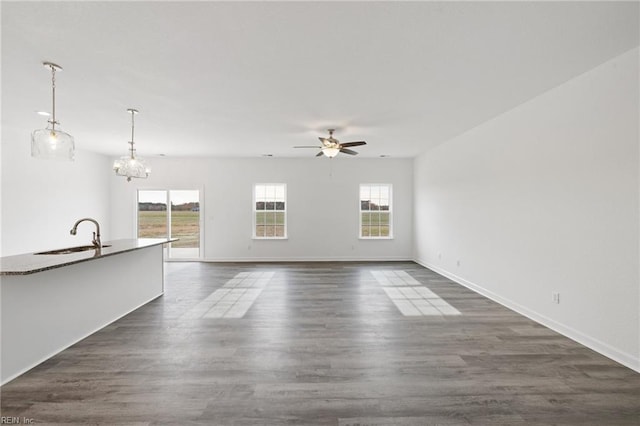 unfurnished living room with dark hardwood / wood-style flooring, sink, and ceiling fan with notable chandelier