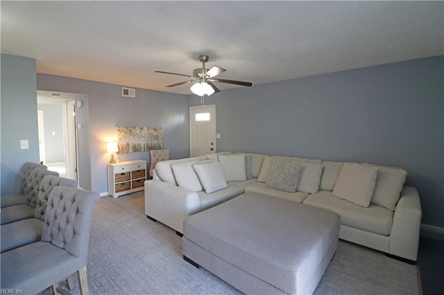 living room with carpet, ceiling fan, and a textured ceiling