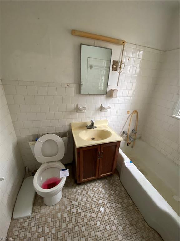 bathroom with vanity, toilet, and tile walls