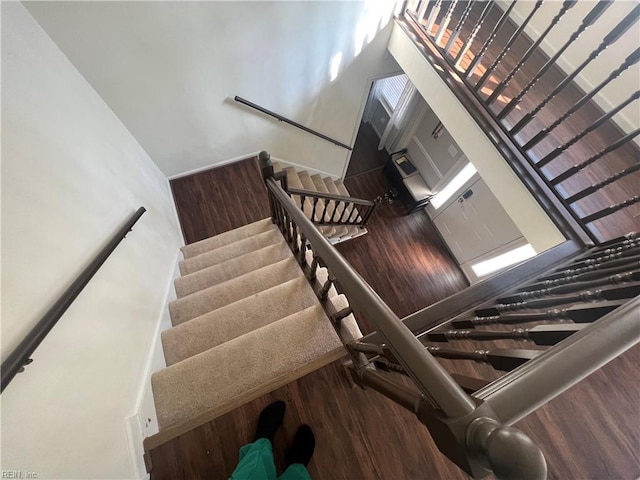 stairway featuring wood-type flooring and a high ceiling