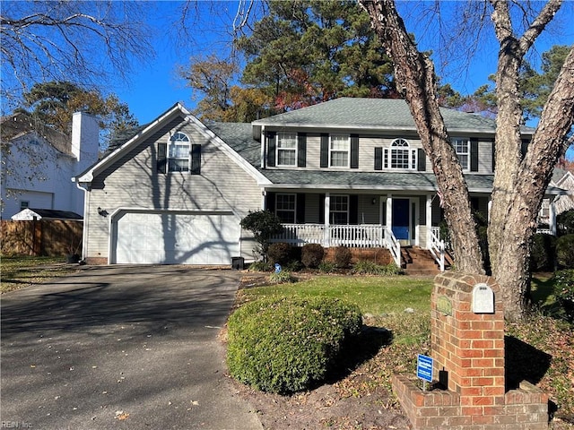 colonial home with a porch, a garage, and a front yard