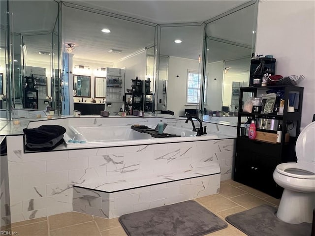 bathroom featuring vanity, tile patterned floors, crown molding, toilet, and tiled tub