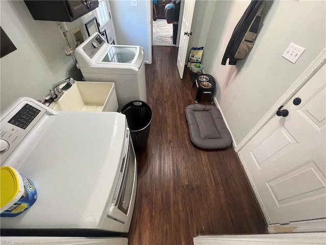 laundry area with washing machine and dryer, sink, and dark hardwood / wood-style floors