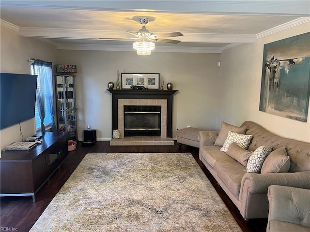 living room with dark hardwood / wood-style floors, ceiling fan, crown molding, and a fireplace