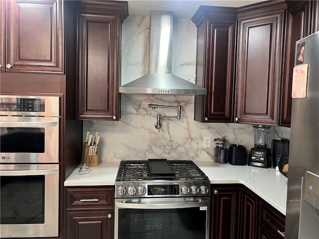 kitchen with wall chimney exhaust hood, stainless steel appliances, and tasteful backsplash