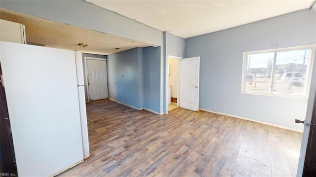 interior space with hardwood / wood-style floors, white refrigerator, and a textured ceiling