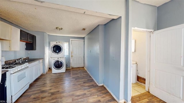 laundry room featuring wood-type flooring, a textured ceiling, stacked washer / drying machine, and sink