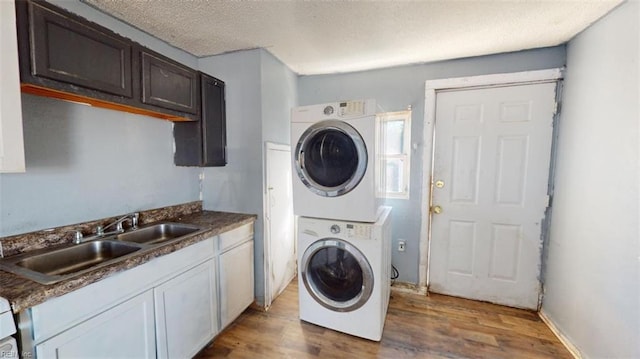 washroom with hardwood / wood-style floors, stacked washer / drying machine, sink, and a textured ceiling