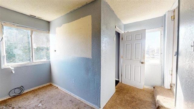 hallway with a textured ceiling and carpet floors