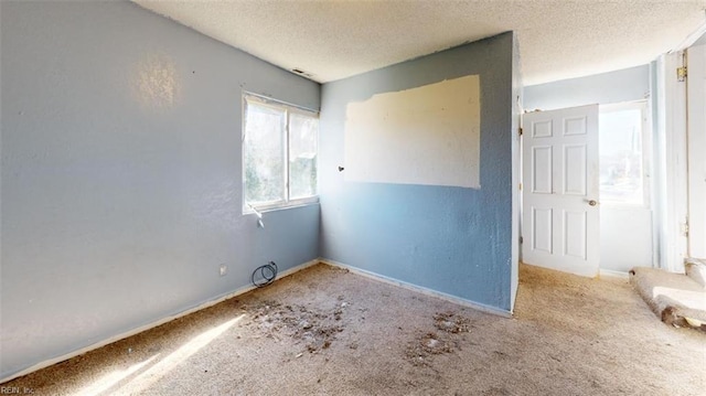 carpeted empty room featuring a textured ceiling