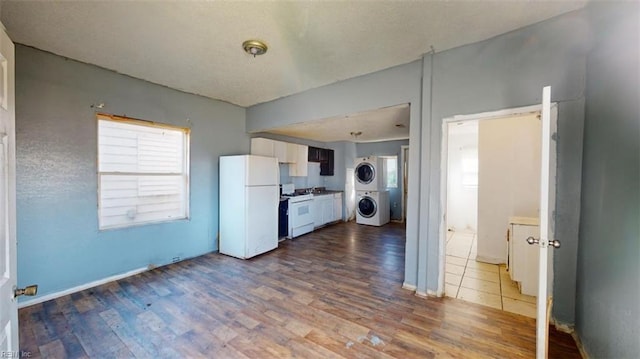 kitchen featuring stacked washer / drying machine, white cabinets, white appliances, and hardwood / wood-style flooring