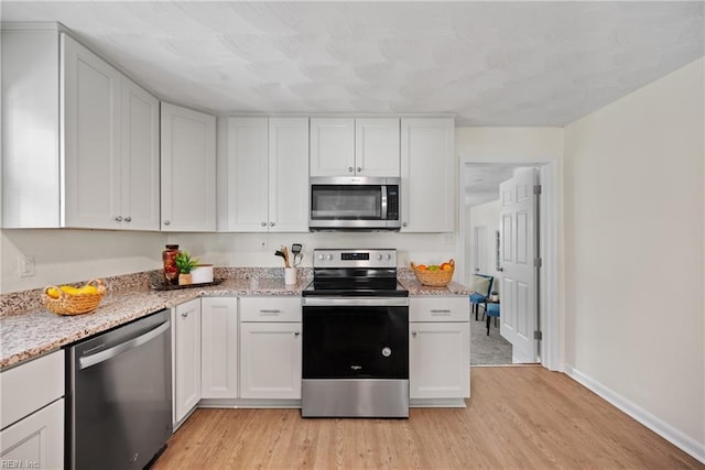 kitchen with white cabinets, light wood-type flooring, and stainless steel appliances