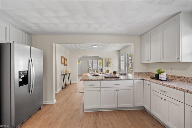 kitchen featuring kitchen peninsula, stainless steel fridge with ice dispenser, light hardwood / wood-style flooring, and white cabinetry