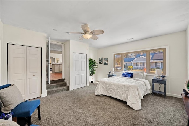 carpeted bedroom featuring ceiling fan and two closets