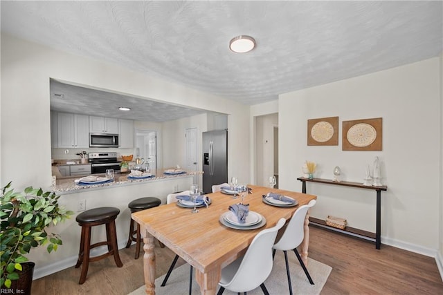 dining space with a textured ceiling and light wood-type flooring