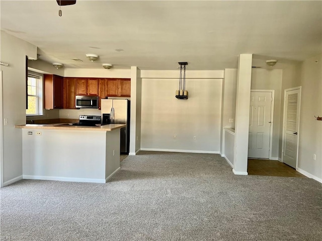 kitchen featuring kitchen peninsula, carpet floors, stainless steel appliances, and decorative light fixtures