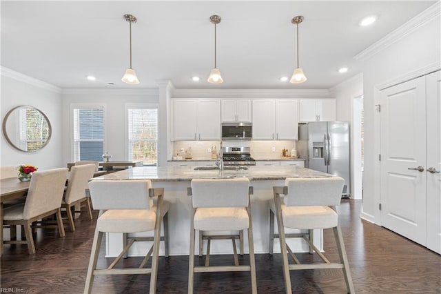 kitchen with a kitchen island with sink, dark wood-type flooring, decorative light fixtures, white cabinetry, and stainless steel appliances