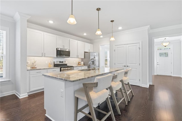 kitchen featuring white cabinetry, an island with sink, hanging light fixtures, and appliances with stainless steel finishes