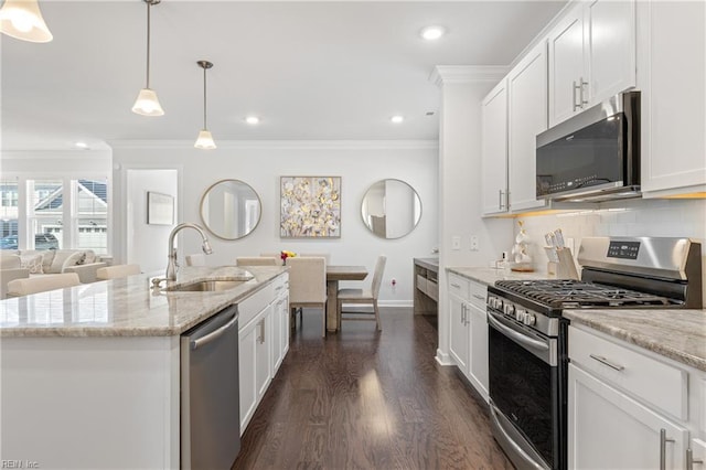 kitchen featuring pendant lighting, white cabinets, a center island with sink, sink, and stainless steel appliances