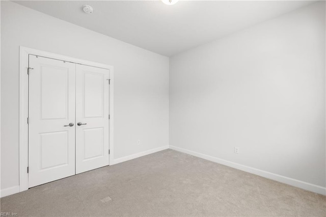 unfurnished bedroom with light colored carpet and a closet