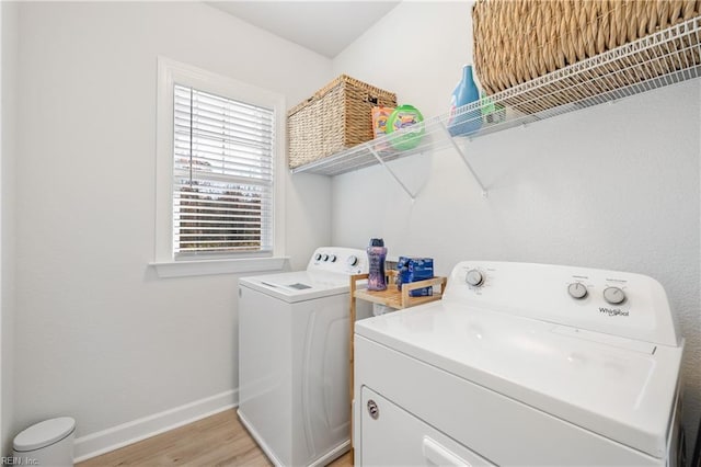 washroom with washing machine and clothes dryer and light hardwood / wood-style flooring