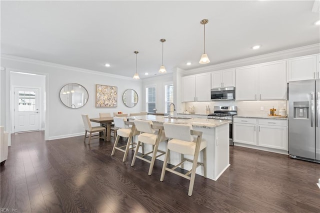 kitchen featuring appliances with stainless steel finishes, a wealth of natural light, pendant lighting, and a kitchen island with sink