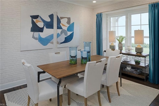 dining area featuring wood-type flooring and brick wall