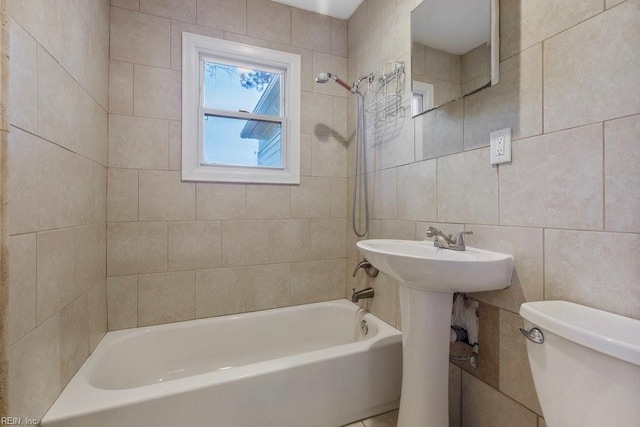 bathroom with tiled shower / bath, tile walls, and toilet